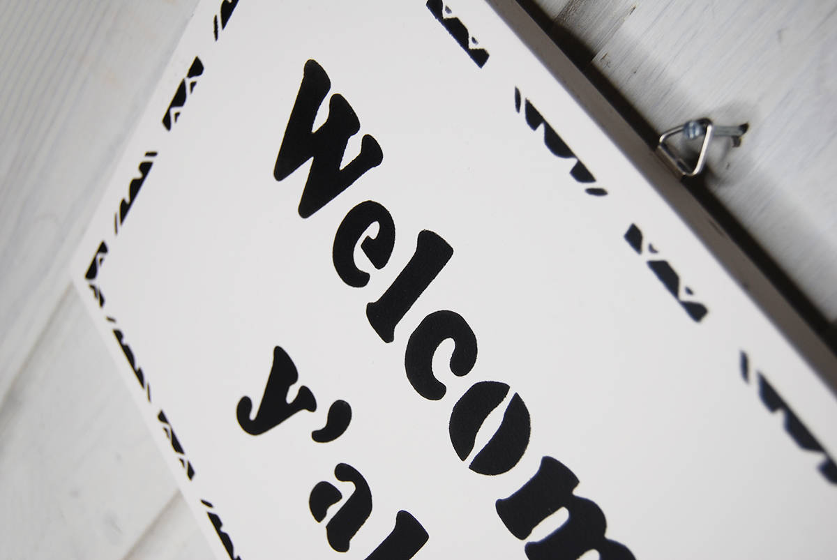 Welcome y'all. Entryway / hall / hallway / porch / veranda / doorway. Welcome wall sign at the door