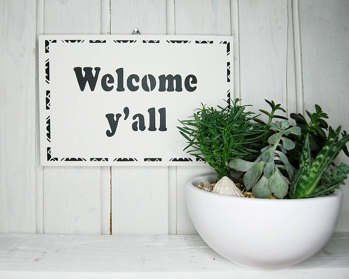 Welcome y'all. Entryway / hall / hallway / porch / veranda / doorway. Welcome wall sign at the door